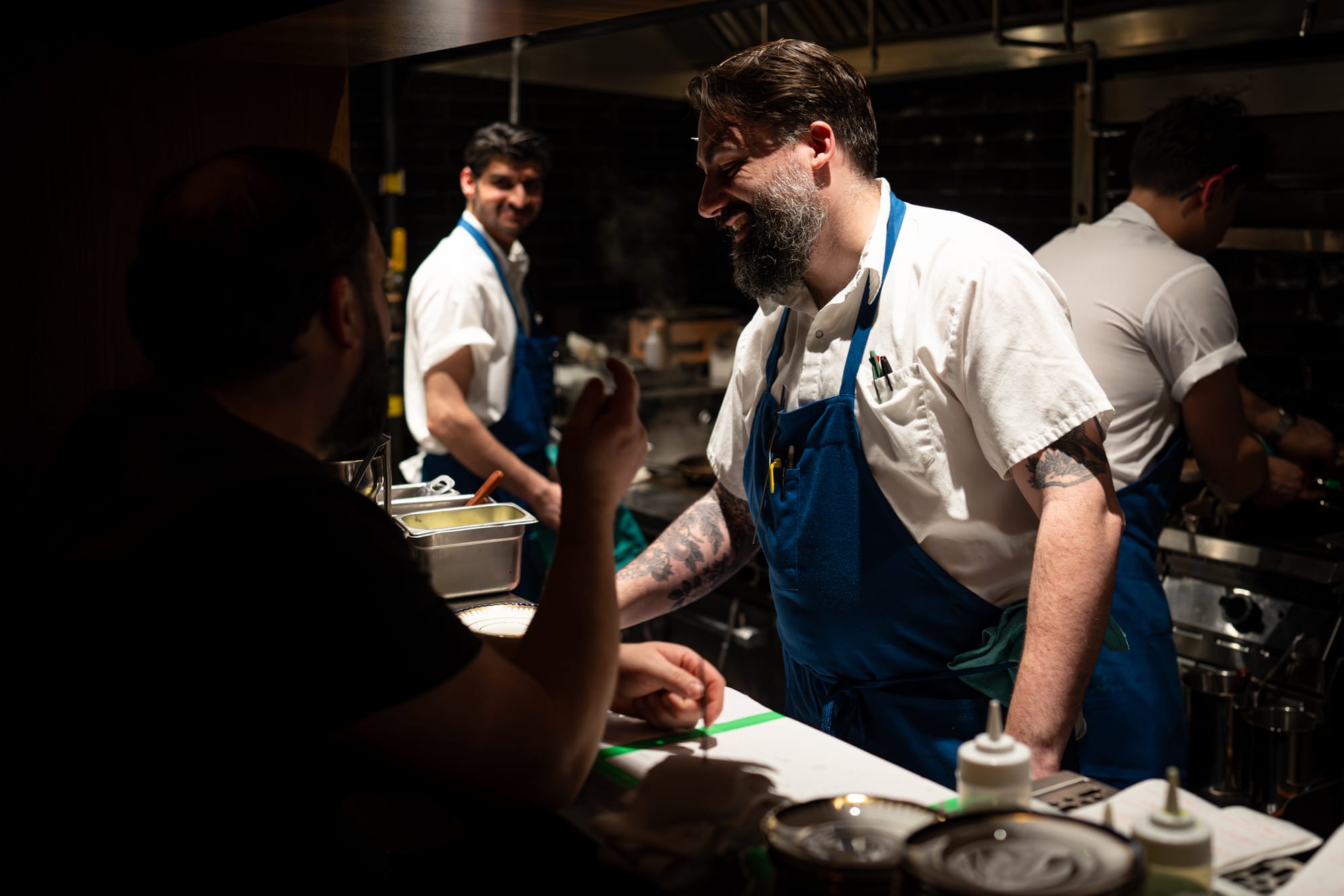 Chef Michael laughing with his team at the pass